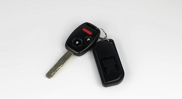 A close-up of a car key and remote on a white background.
